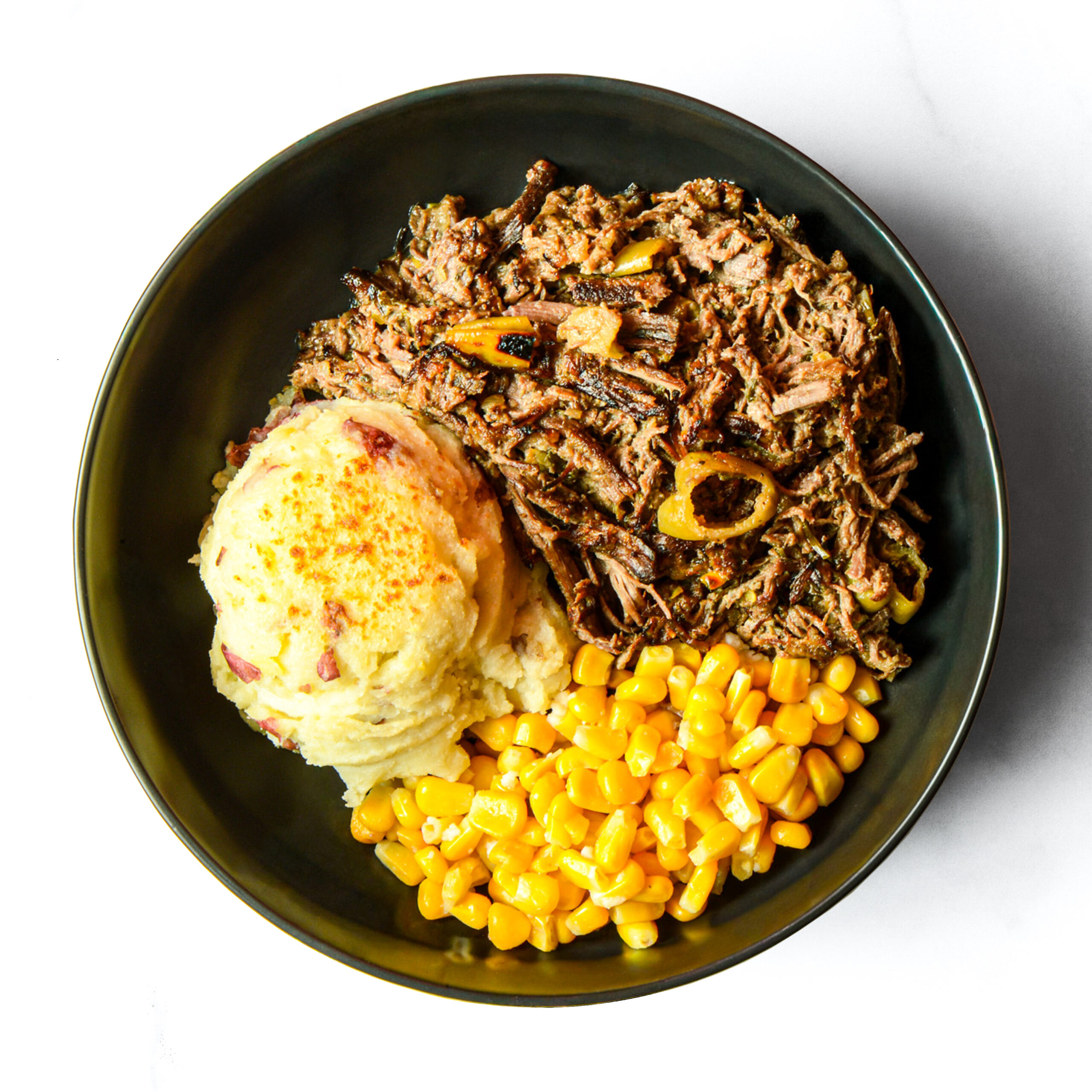 The Redneck Riviera: Shredded pot roast with onions, mashed potatoes with skin, and yellow corn served in a black bowl.