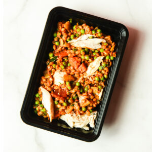 A black meal tray of Cluck The Bean, featuring peas, lentils, diced tomatoes, and shredded chicken on a white surface.