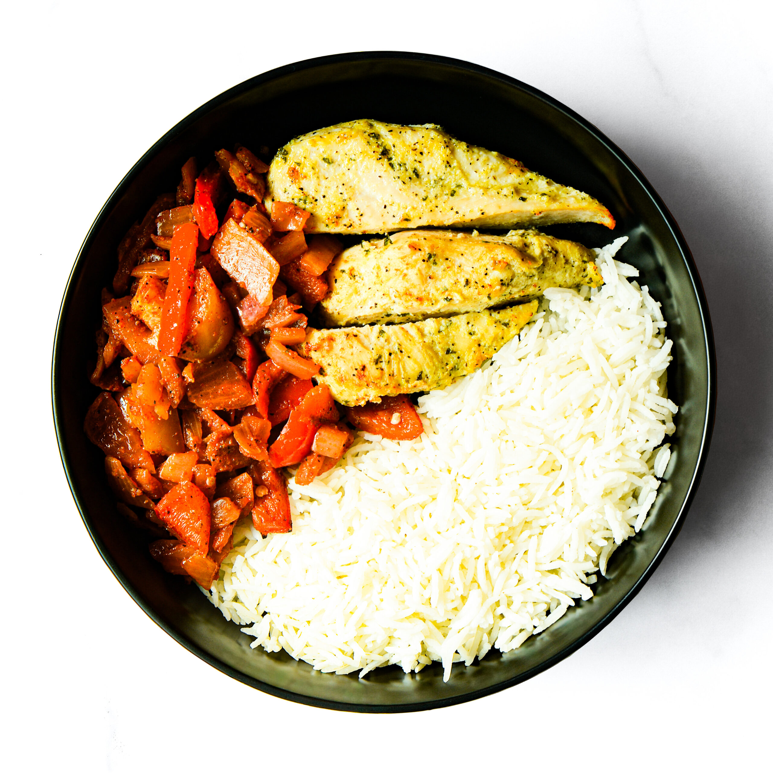 Operation Cajun Fit features a black bowl filled with white rice, sliced chicken breast, and a medley of red bell peppers and onions.