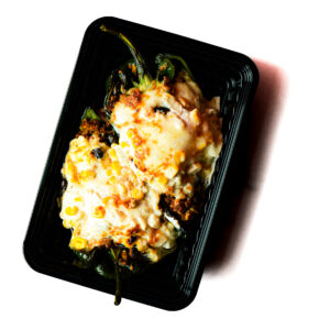 Operation Cajun Fit is a black plastic container filled with stuffed poblano peppers, topped with melted cheese and corn.