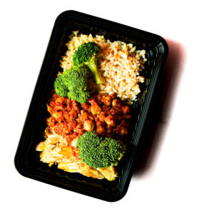 Operation Cajun Fit: A black plastic meal container featuring brown rice, chickpeas in tomato sauce, shredded chicken, and broccoli on a white background.