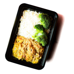 Operation Cajun Fit: A black tray with white rice, steamed broccoli, and shredded meat in yellow sauce on a white background.