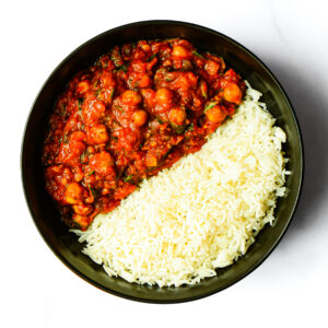 A top-down view of Engine 38 Tortellini in a black bowl, with white rice on one side and chickpea tomato curry on the other.
