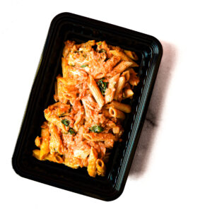 A black plastic container of Chickpeas & Beef? Savvy! filled with beef, chickpeas, and sauce sits against a white background.