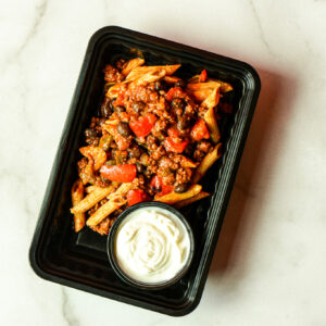 Flexican Fiesta: Penne pasta with ground meat, peppers, and sauce in a black plastic container, served with white dipping sauce.