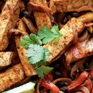 Close-up of Pasta Voodoo: cooked tofu strips with onions, red bell peppers, black beans, and fresh cilantro garnish.