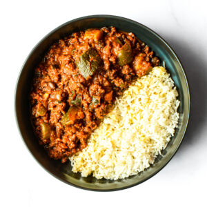 The Nacho Libre Gains Bowl features white rice on one side and a chunky, tomato-based stew with vegetables and ground meat on the other.