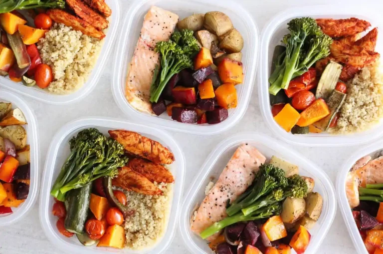 Six meal prep containers filled with salmon or chicken, quinoa, roasted vegetables, and broccolini—perfect for convenient Weight Loss Meal Delivery.