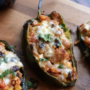 Let Me Stuff You, With My Poblano: a poblano pepper stuffed with rice, beans, veggies & cheese, finished with cilantro on a wooden board.