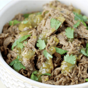 Wake Up & Get Porked: Shredded pork with green salsa and fresh cilantro, served in a white bowl.