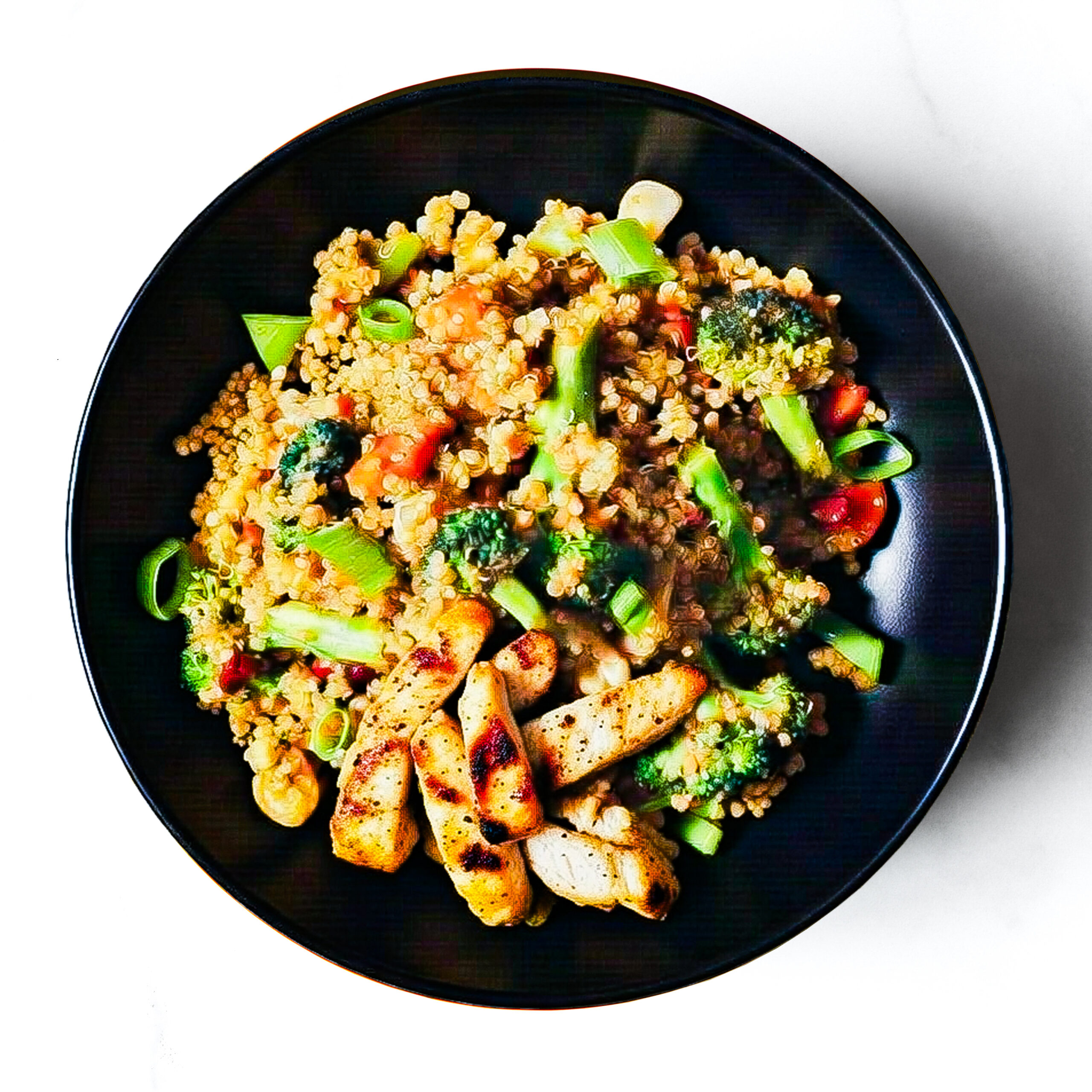 A black bowl filled with The F*d Up Fajita—quinoa stir-fry with broccoli, carrots, green onions, and grilled chicken breast—on a white background.
