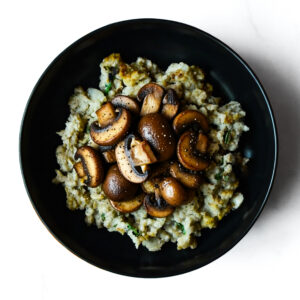 The F*d Up Fajita served in a black bowl, filled with mashed potatoes and sautéed sliced mushrooms, shown from above on a white surface.