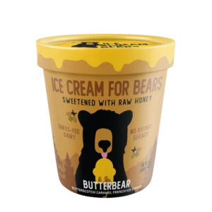 A yellow and brown pint labeled Queen & Bean, sweetened with raw honey, featuring a bear illustration, grass-fed dairy, and no refined sugars.