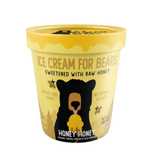 A yellow Queen & Bean ice cream container features a bear illustration, honey graphics, and text about raw honey, grass-fed dairy, and no refined sugars.