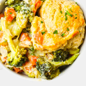 Enjoy a bowl of Piehard, a vegetable pot pie with broccoli, carrots, a flaky biscuit topping, and chopped parsley.