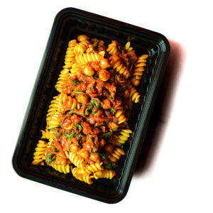 A black plastic container filled with rotini pasta topped with a tomato-based sauce, chickpeas, and herbs.