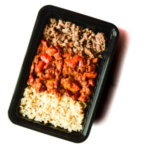 A black plastic meal tray containing cooked ground beef, a chili mixture with beans and peppers, and a serving of brown rice.