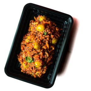 A black plastic tray containing a serving of cooked food with green olives, herbs, and a tomato-based sauce.