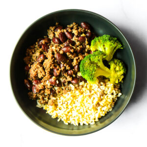 A bowl containing ground meat with kidney beans, steamed broccoli florets, and cooked rice, arranged in sections.