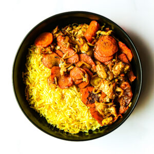 A black bowl filled with yellow rice and a cooked mixture of sliced carrots, chicken, and onions.