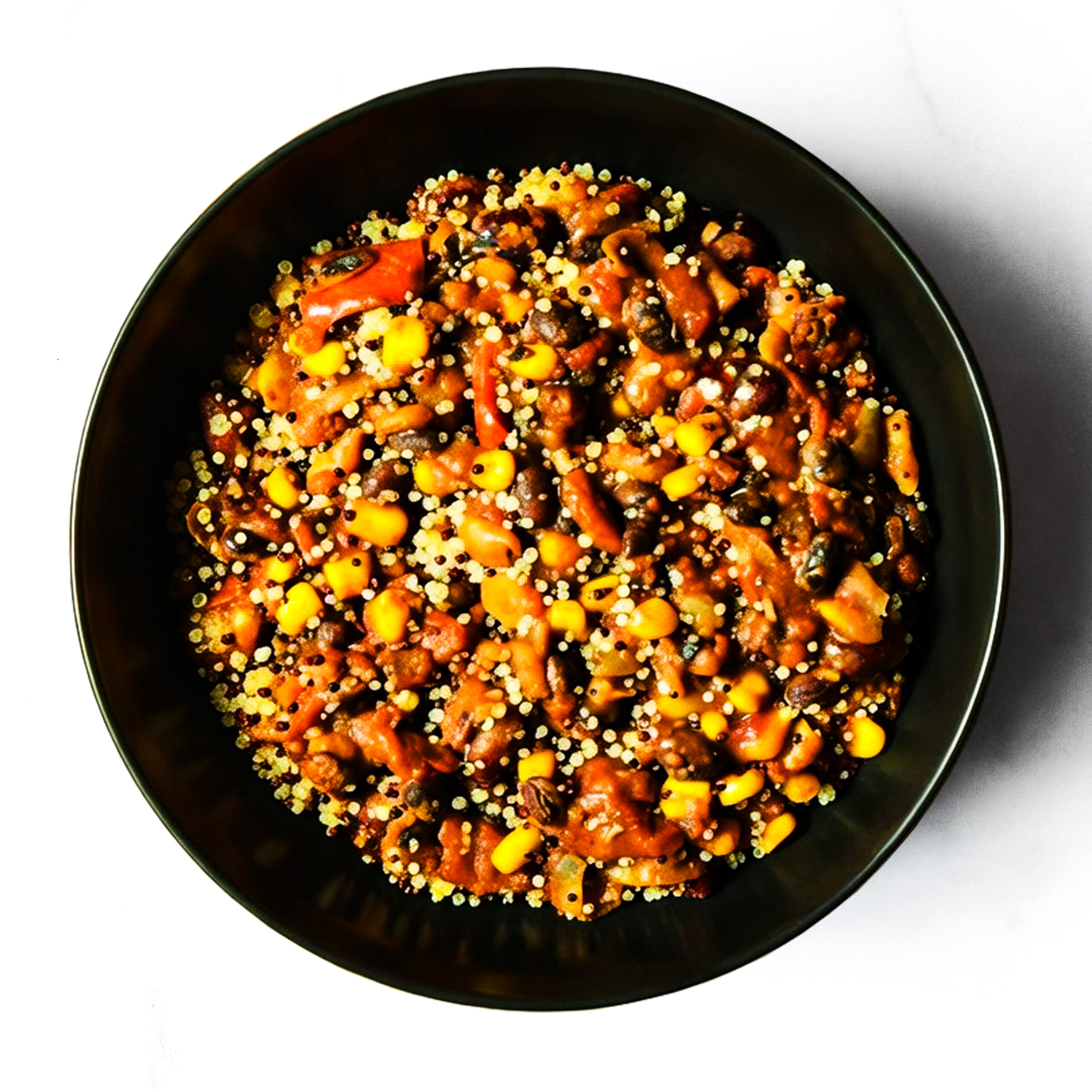 A black bowl filled with a mixed dish of beans, corn, tomato, and grains, photographed from above on a white background.